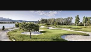 a golf course with a tree in the middle at CoolTainer retreat: Sustainable Coastal forest Tiny house near Barcelona in Castelldefels