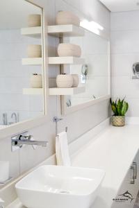 a white bathroom with a sink and a mirror at Black Marlin Apartments in Pereybere
