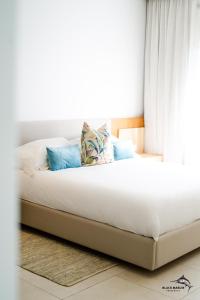 Bett mit weißer Bettwäsche und blauen Kissen in der Unterkunft Black Marlin Apartments in Pereybere