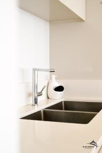 eine Küche mit einem Waschbecken in einer weißen Küche in der Unterkunft Black Marlin Apartments in Pereybere