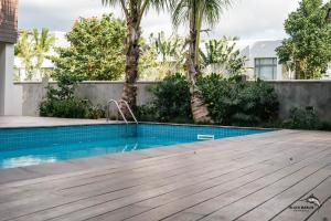 a swimming pool with a wooden deck next to a building at Black Marlin Apartments in Pereybere