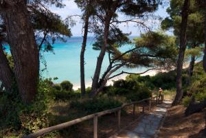 a person walking down a path near the beach at Palladium Hotel in Kriopigi