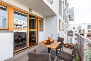 Apartament dysponuje balkonem z drewnianym stołem i krzesłami. w obiekcie SuperApart Chełmska 9 w Warszawie