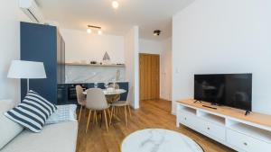 - un salon avec un canapé, une télévision et une table dans l'établissement Apartamenty Sun & Snow Baltic Twins, à Sztutowo