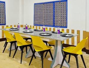 a dining table with yellow chairs in a room at Manas Jungle Retreat in Jyoti Gaon