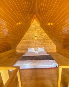 a bed in a wooden cabin with a wooden ceiling at Godieng Cabin 2 in Dieng