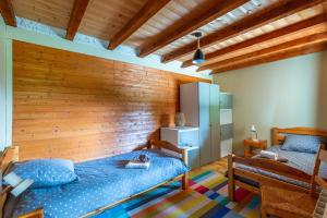 a bedroom with a wooden wall and two beds at Chalet L'oréade in Manigod