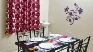 mesa de comedor con sillas y cortina roja en Naadi Nest - 2 Bedroom Service Apartment, en Thanjāvūr