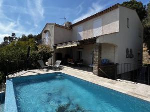 a villa with a swimming pool in front of a house at La Villa Pavilou in Le Lavandou