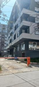 un gran edificio con un estacionamiento delante de él en Apartman Nikol, en Kumanovo