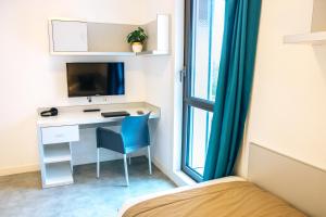 una camera da letto con una scrivania con una sedia blu e un letto di Twenty Business Flats Lille Grand Stade a Villeneuve d'Ascq