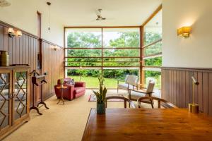 un salon avec une table et une grande fenêtre dans l'établissement amã Stays & Trails Forest Home, Hosur, à Hosur