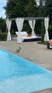 a bed in a canopy next to a pool at Le Domaine in La Chapelle-de-Guinchay