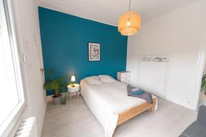 - une chambre avec un lit et un mur bleu dans l'établissement KASA LYONNAISE - Proche Lyon, Transports, Tout équipé, à Grigny