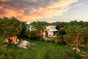une maison au milieu d'un champ avec des arbres dans l'établissement amã Stays & Trails Forest Home, Hosur, à Hosur