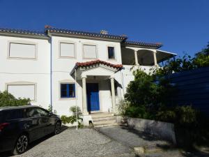 a white house with a car parked in front of it at Casa Cecilia Seaside Serenity and Coastal Charm in Coimbrão