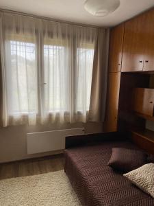 a bedroom with a bed and a window with curtains at Къща за гости Ива 