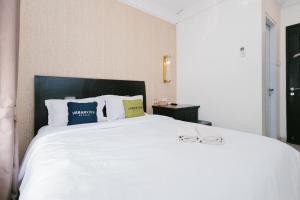 a bedroom with a white bed with two glasses on it at Urbanview Hotel Sultan Palace Malang by RedDoorz in Dau
