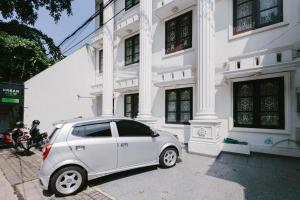 a white car parked in front of a building at Urbanview Hotel Sultan Palace Malang by RedDoorz in Dau