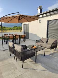 a patio with chairs and a table and an umbrella at Villa Ritual in Mostar