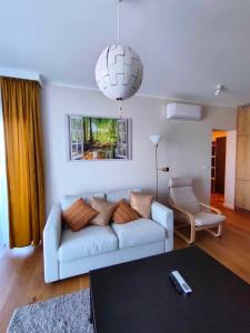 a living room with a white couch and a chandelier at Apartament Miodowy - Penthouse z balkonem in Kudowa-Zdrój