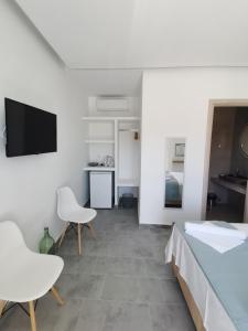 um quarto com uma cama e duas cadeiras e uma televisão em Aetherian Suites em Loutrá