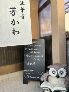 un cartel con un búho sentado junto a un cartel con escrito en Guesthouse法華寺Yoshikawa, en Nara