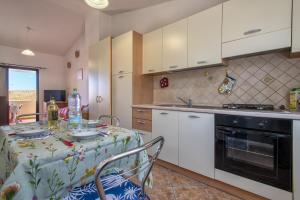 a kitchen with a table and a kitchen with white cabinets at Bilocale 1 medio Trinita' D'agultu in Trinità d'Agultu e Vignola