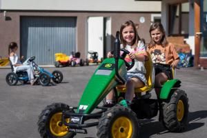 dos jovencitas montadas en un tractor de juguete en Ferienwohnungen Plattnerhof, en Terfens