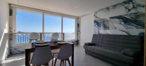 a dining room with a table and chairs and a couch at Principado Benidorm Suites Levante in Benidorm
