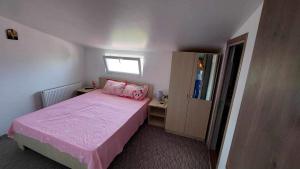 a small bedroom with a pink bed and a window at Casa Mario in Isverna