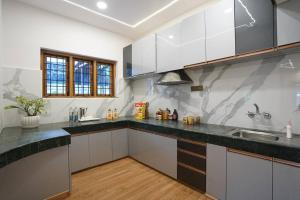 a kitchen with white cabinets and black counter tops at Le Mistral, Kodai - Luxury Villa in Kodaikānāl
