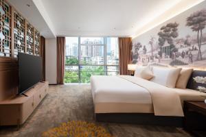 sypialnia z dużym łóżkiem i dużym oknem w obiekcie Guangzhou Wogo Yuanbao Hotel - Zhujiang New Town with free coffee w Guangzhou