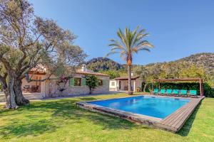 a house with a swimming pool and a palm tree at Villa Can Gallardo by Sealand Villas in Pollença