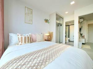 - une chambre blanche avec un grand lit blanc et des oreillers dans l'établissement CARAMEL COZY @ ATMOZ BANGNA (Si Iam MRT.), à Ban Khlong Samrong