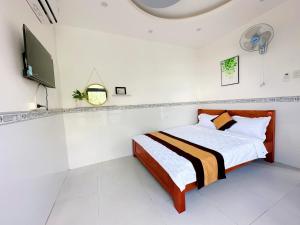 a white bedroom with a bed and a tv at Hotel Thuý Nguyễn in Cà Sang