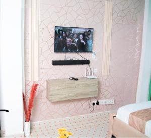 Habitación con TV en una pared rosa en Emap Homes- Golf studio, en Kilifi