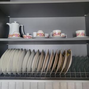 une étagère avec des assiettes et des tasses dessus dans l'établissement Φιλόξενο σπίτι στο Βόλο, à Vólos