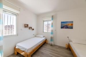 a bedroom with two beds and two windows at Desert and Sea-penthouse Full Sea view in Eilat