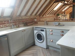 a kitchen with a washing machine and a sink at Luxury barn with hot tub (Dogs Welcome) in Roughton