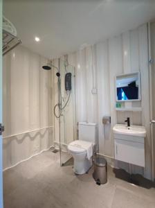 uma casa de banho com um chuveiro, um WC e um lavatório. em Solesor Kampong Beach Resort em Porto Dickson