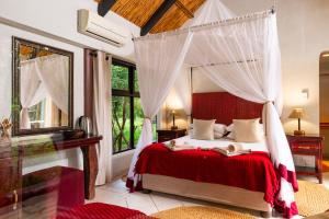 a bedroom with a canopy bed and a large window at Leopard Walk Lodge in Hluhluwe