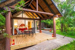 a large wooden deck with a table and chairs at Leopard Walk Lodge in Hluhluwe