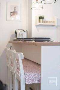 una cocina con una encimera con dos taburetes blancos en N-apartament Wadowice, en Wadowice