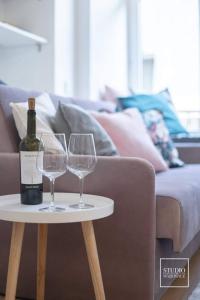 two wine glasses on a table next to a couch at N-apartament Wadowice in Wadowice