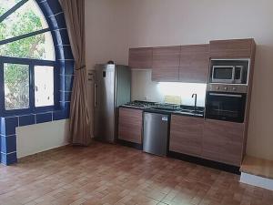 una cocina con armarios y electrodomésticos de madera y una ventana en Auberge du Marabout en Sidi Kaouki