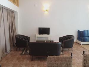 西迪考烏奇的住宿－杜蘇斯馬拉波特旅館，客厅配有椅子和一张桌子及电视