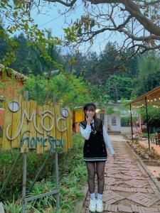 a woman standing in front of a sign at Mộc House in Mộc Châu