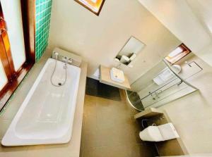 ein Badezimmer mit einer weißen Badewanne und einem Waschbecken in der Unterkunft Cozy house with 3 big bedrooms in Ban Suan