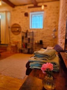 a stack of towels on a table with a vase with a flower at Chamade en Beaujolais in Anse